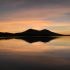 Island silhouette reflecting in calm water at sunset