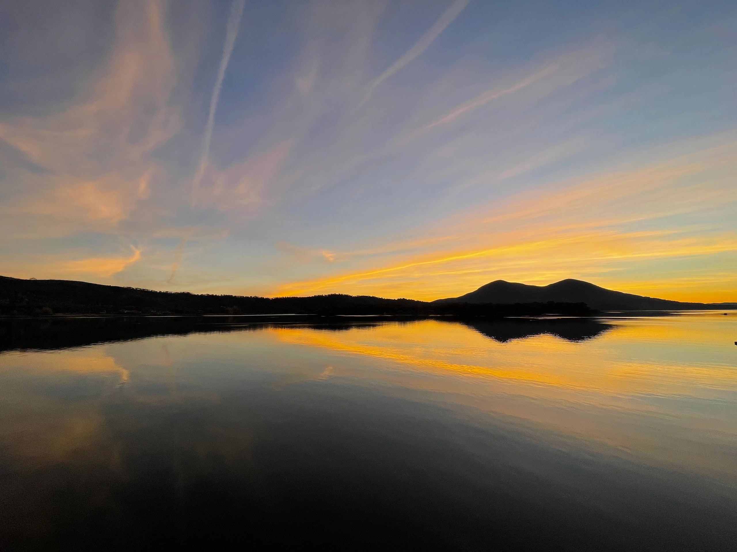 Golden sunset over a calm lake with mountain reflection