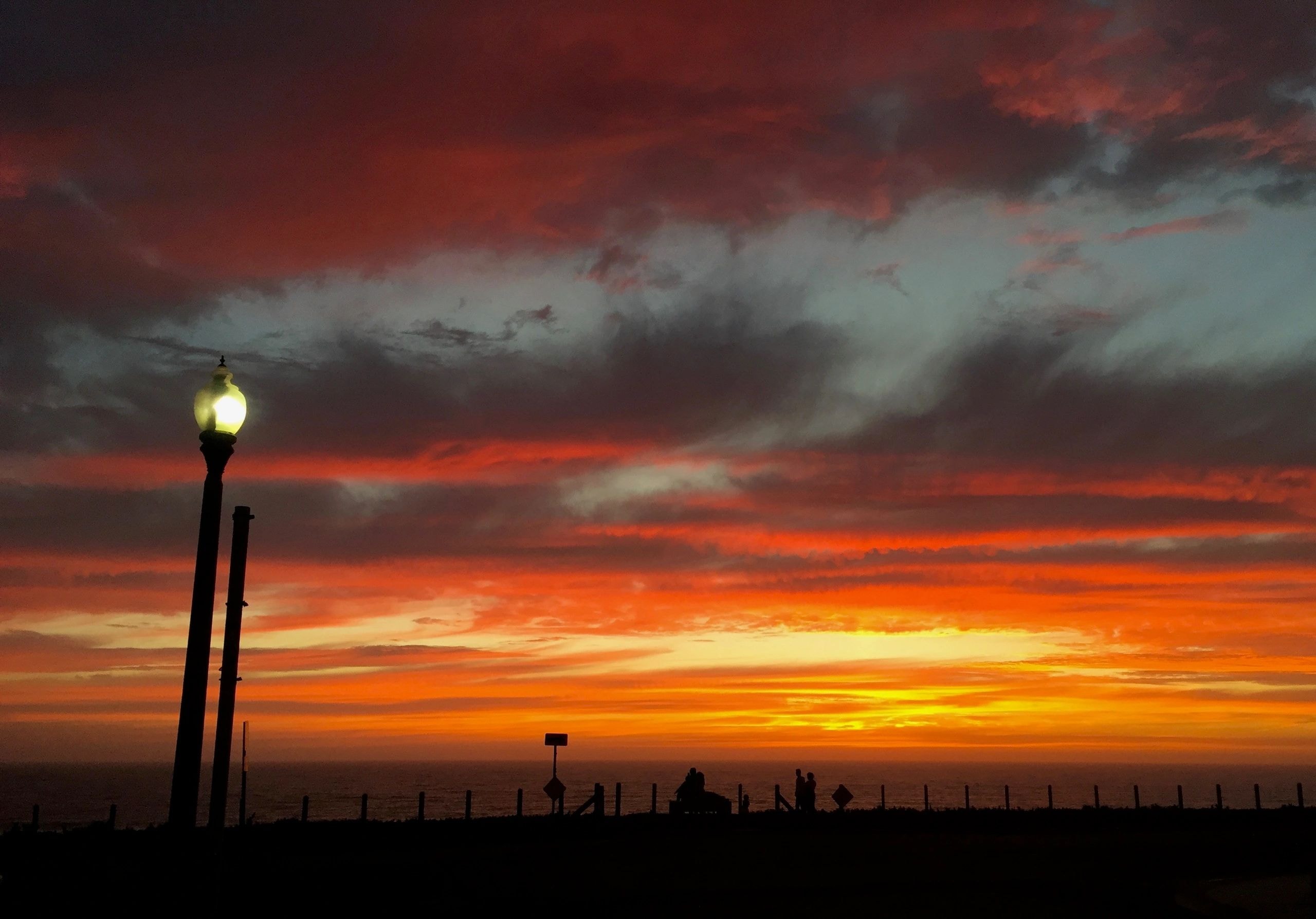 Street lamp glowing against dramatic sunset sky