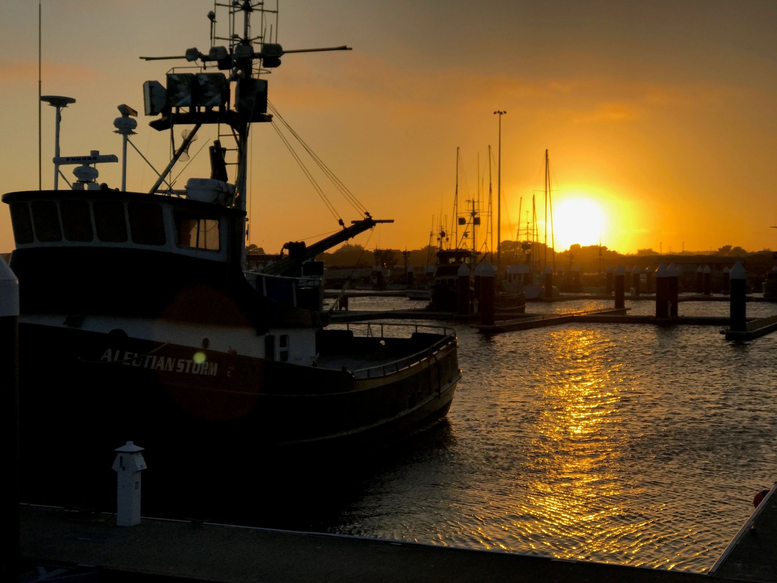 Fishing boats moored at harbor sunset